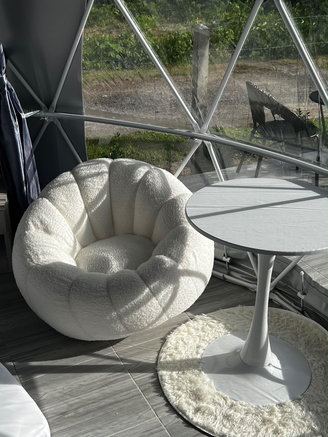 A soft chair and round table inside a sunlit dome at Wanasa